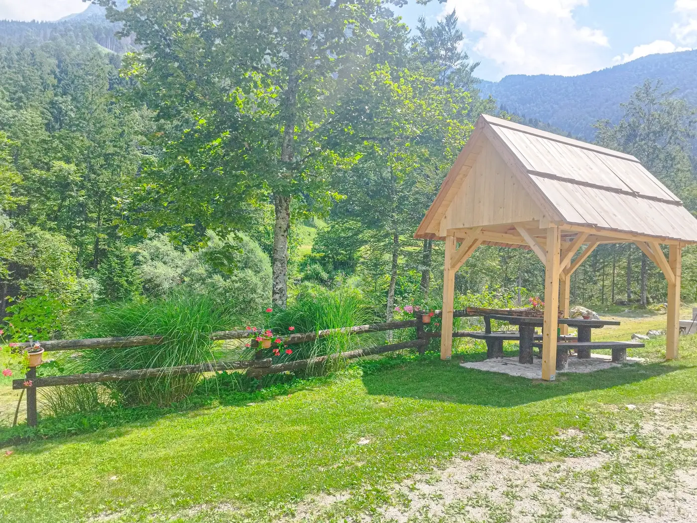 Lesena senčnica z mizo in klopmi na travniku