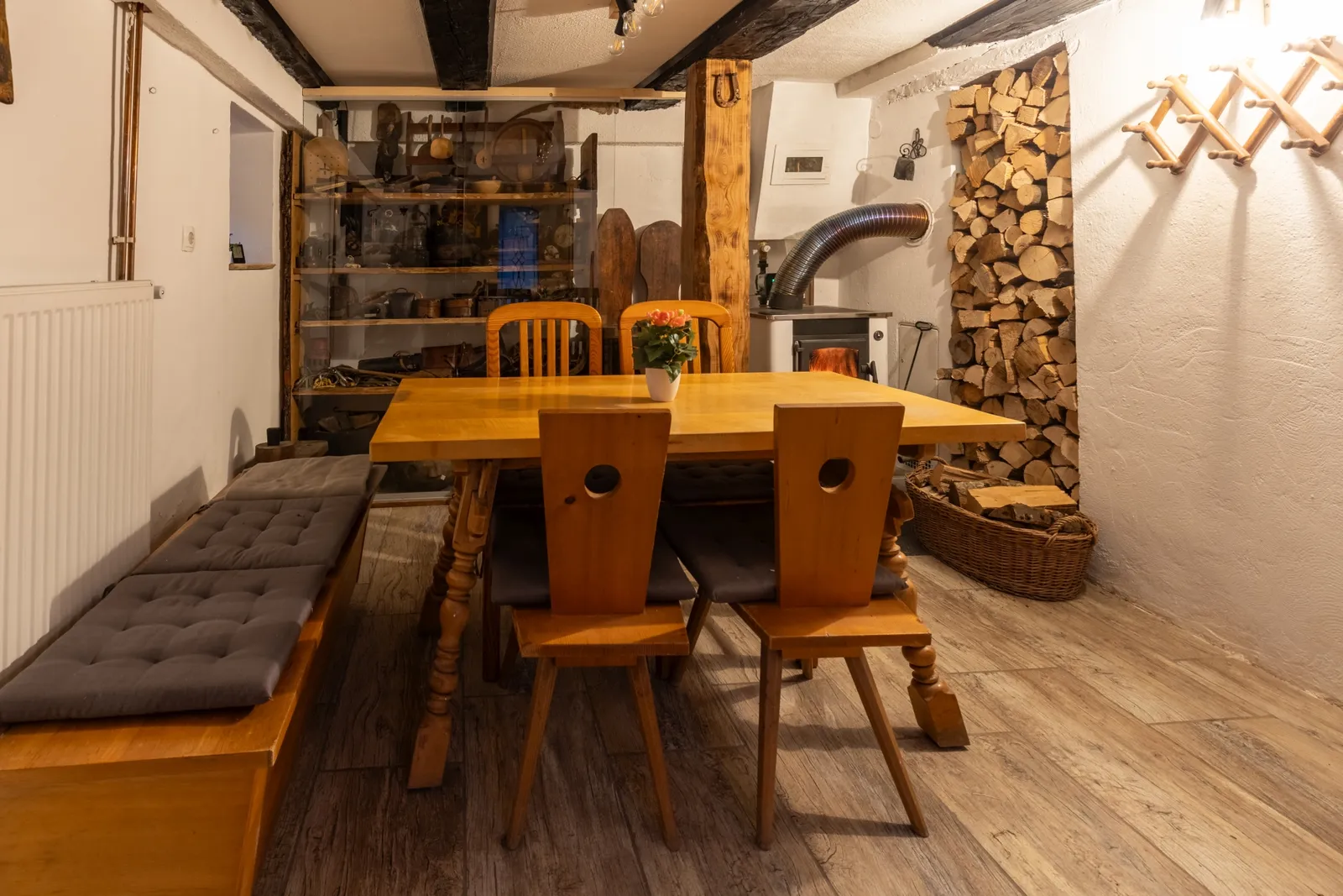 Spodnja jedilnica z lesenimi tramovi, klopjo in pečjo na drva